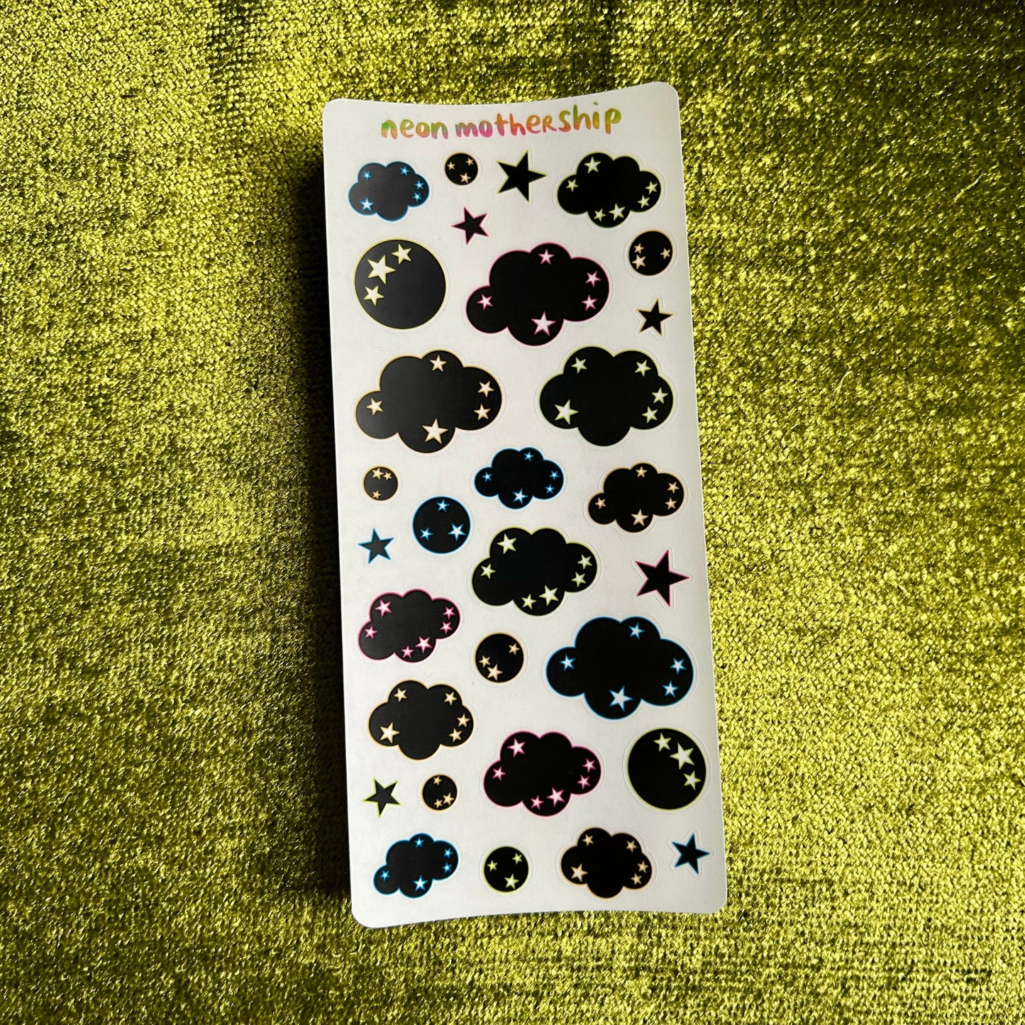 Sheet of black cloud and star-shaped stickers on a green textured background