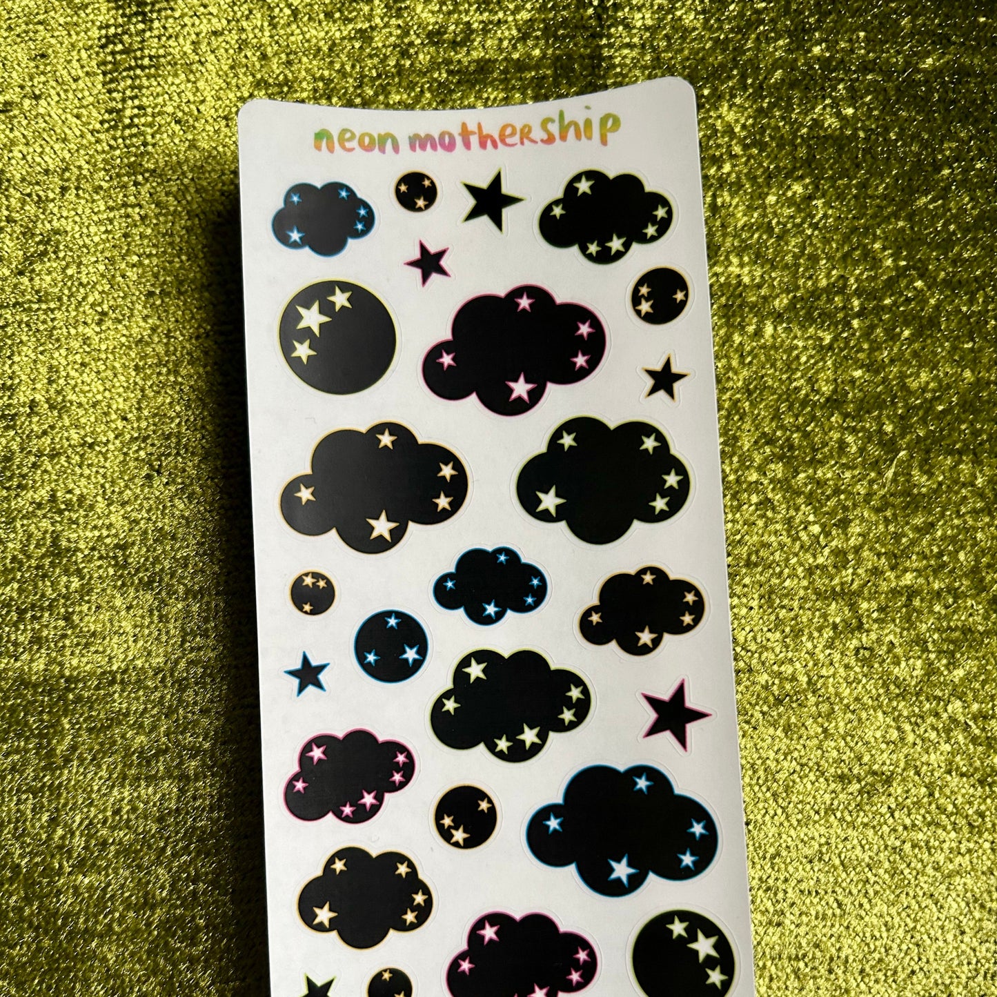 Sticker sheet with cloud and star designs on a green textured background