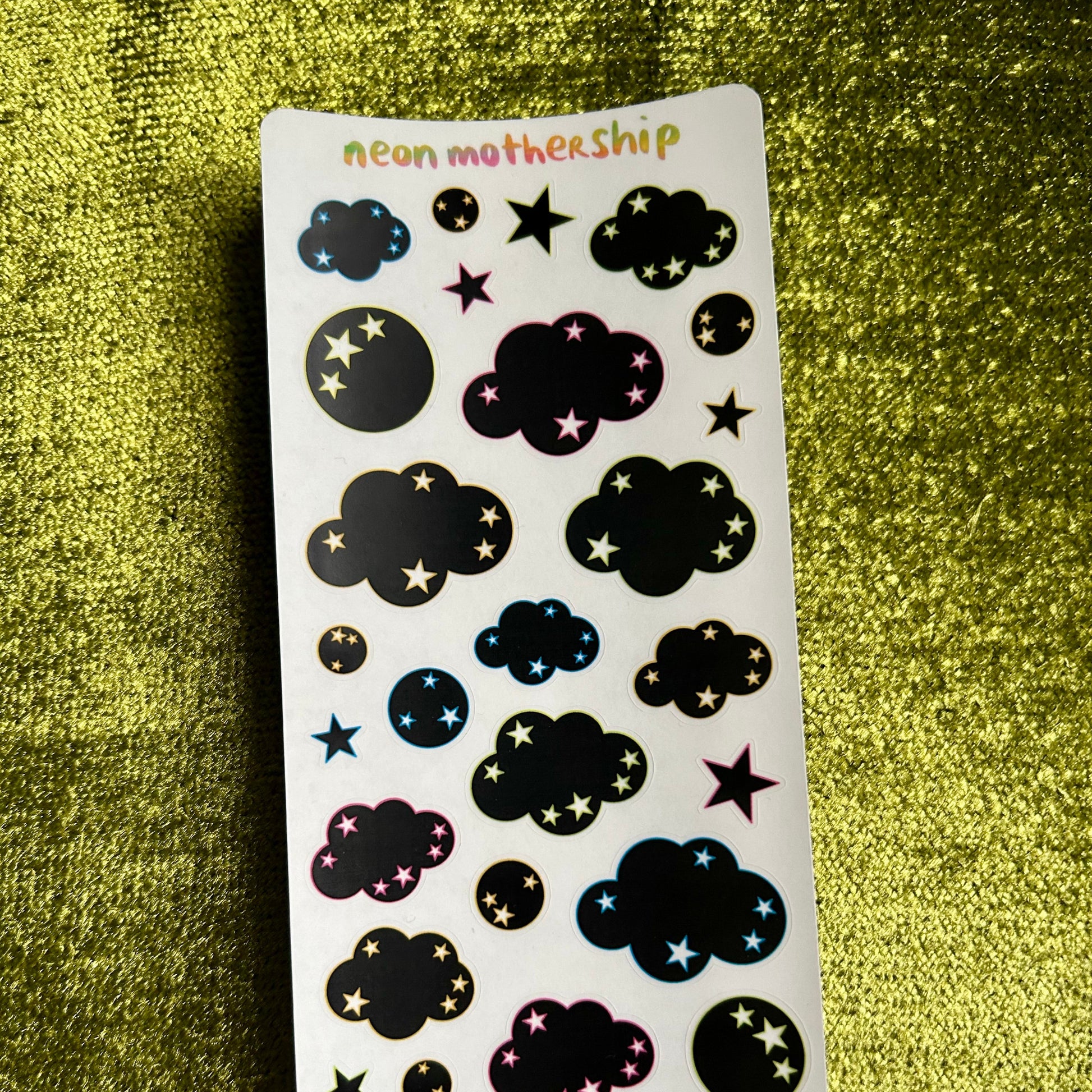 Sticker sheet with cloud and star designs on a green textured background