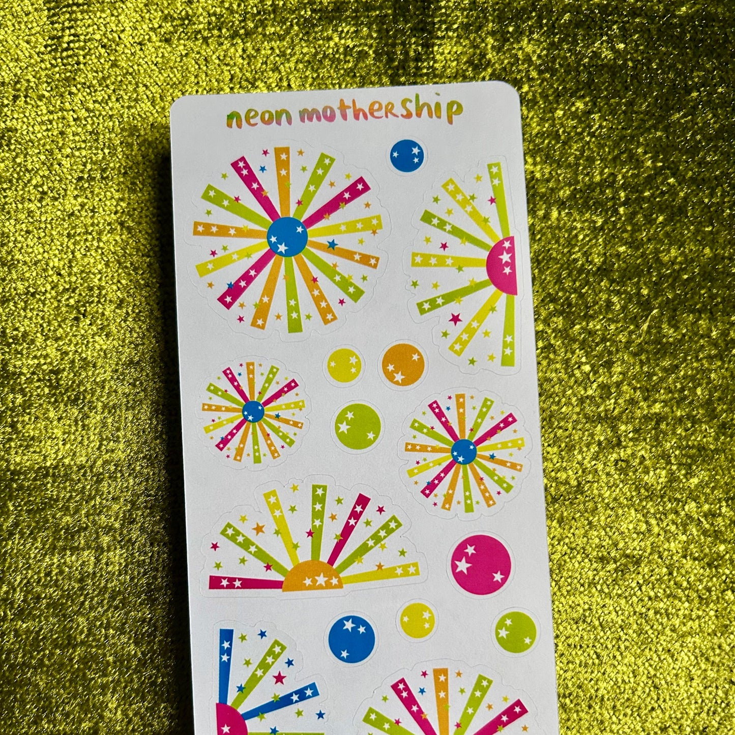 Colorful sticker sheet with starburst designs on a green textured background