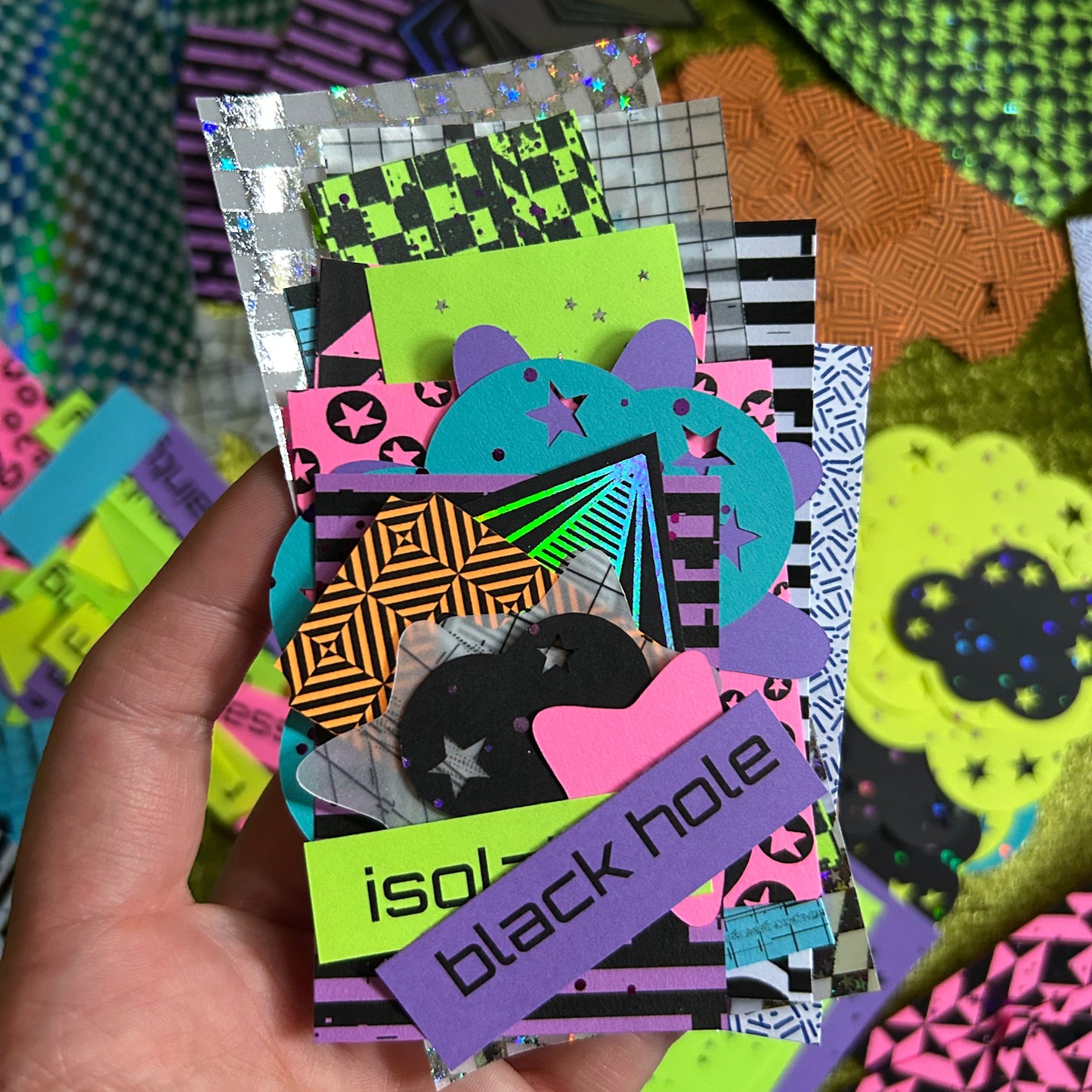 hand holding neon paper scraps with space and pop punk themed designs