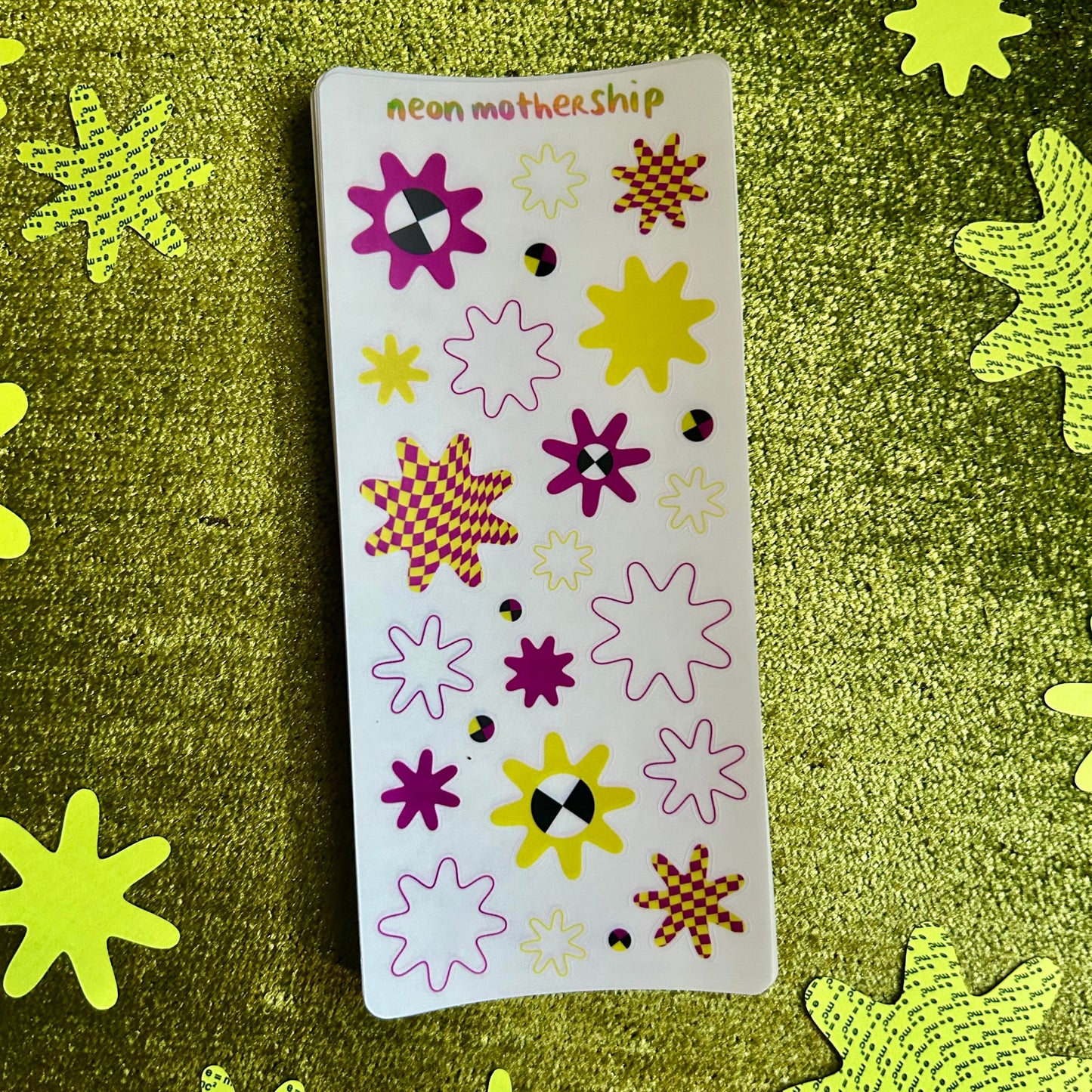 Sheet of colorful star-shaped stickers on a green textured background with additional star stickers.