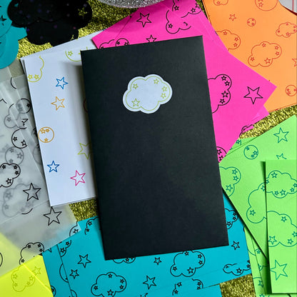 Black envelope with cloud design on a colorful background with star and moon patterns.