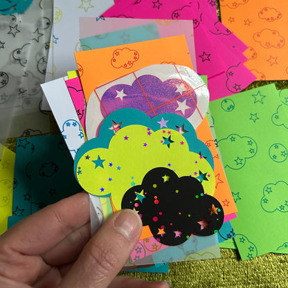 Hand holding a colorful paper cutout with star patterns on a textured surface.