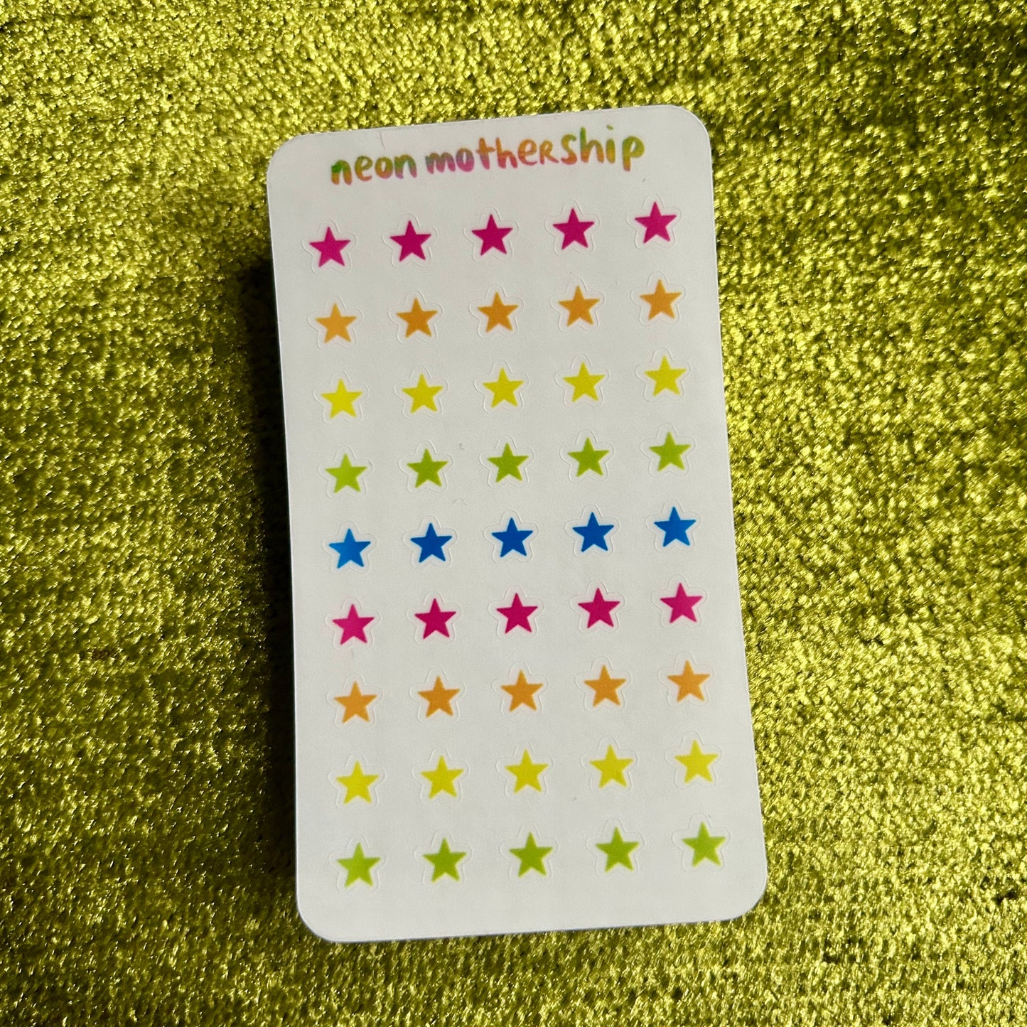 sticker sheet with colorful star stickers on a green glittery background