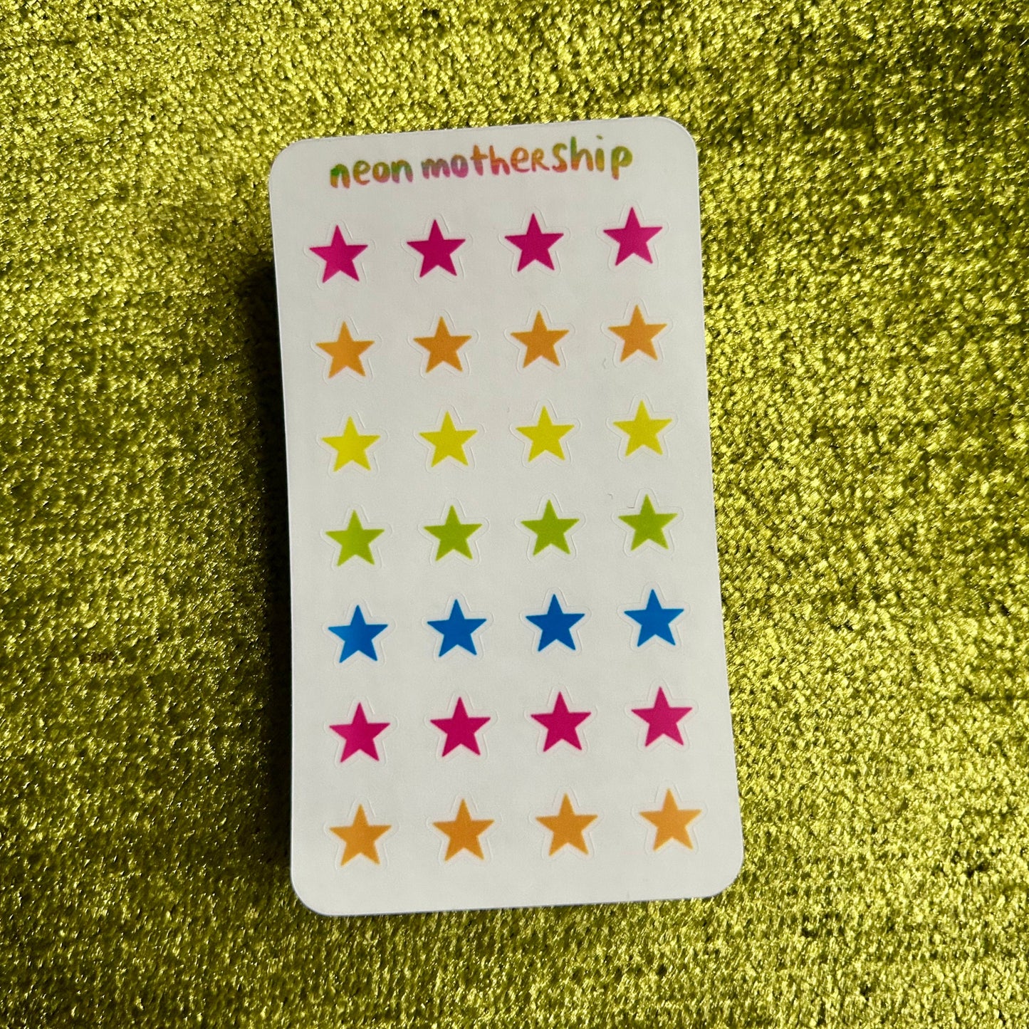 sticker sheet with colorful star stickers on a green glittery background