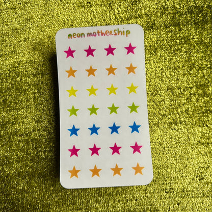 sticker sheet with colorful star stickers on a green glittery background