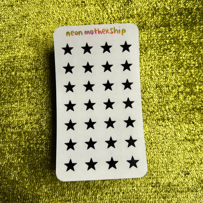 Sheet of black star-shaped stickers on a green textured background