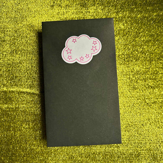 Black envelope with a pink cloud-shaped sticker on a green textured surface