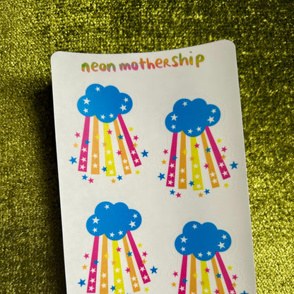 sticker sheet with blue cloud designs and colorful rainbows on a green textured background