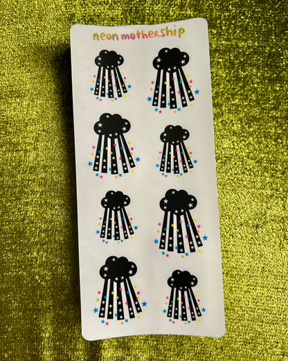 Sheet of black cloud-shaped stickers with colorful dots on a green textured background