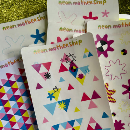 Colorful geometric patterned stickers with 'neon motherShip' branding on a textured surface.