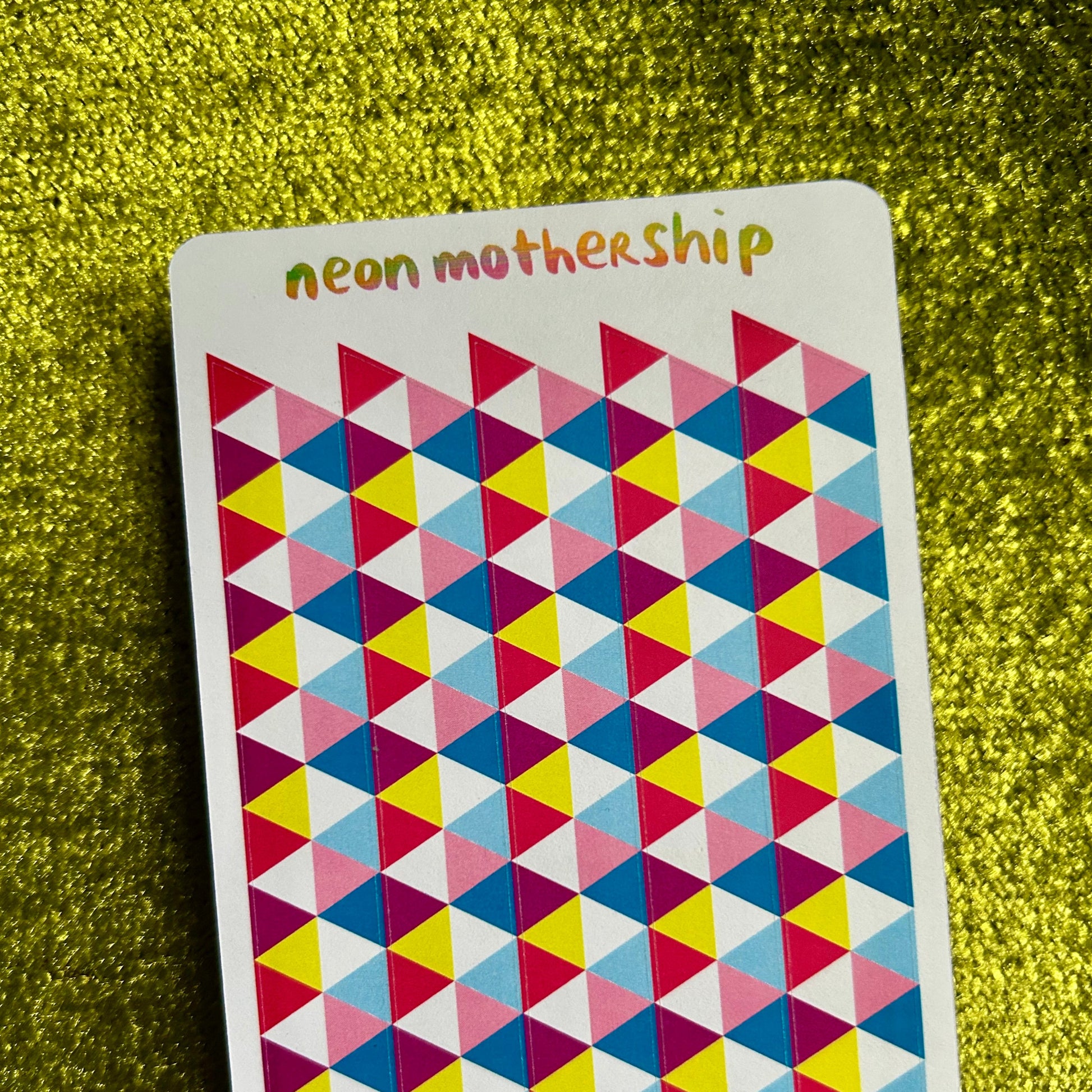 Colorful geometric patterned sticker sheet with 'neon mothership' text on a green textured background