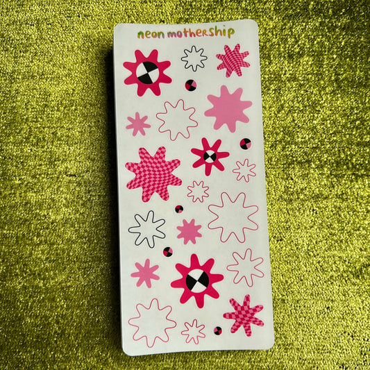 Sheet of star-shaped stickers with pink and white designs on a green textured background
