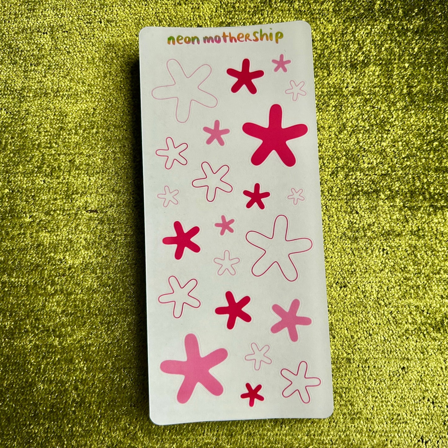 sticker sheet with pink and red star-shaped stickers on a green textured background