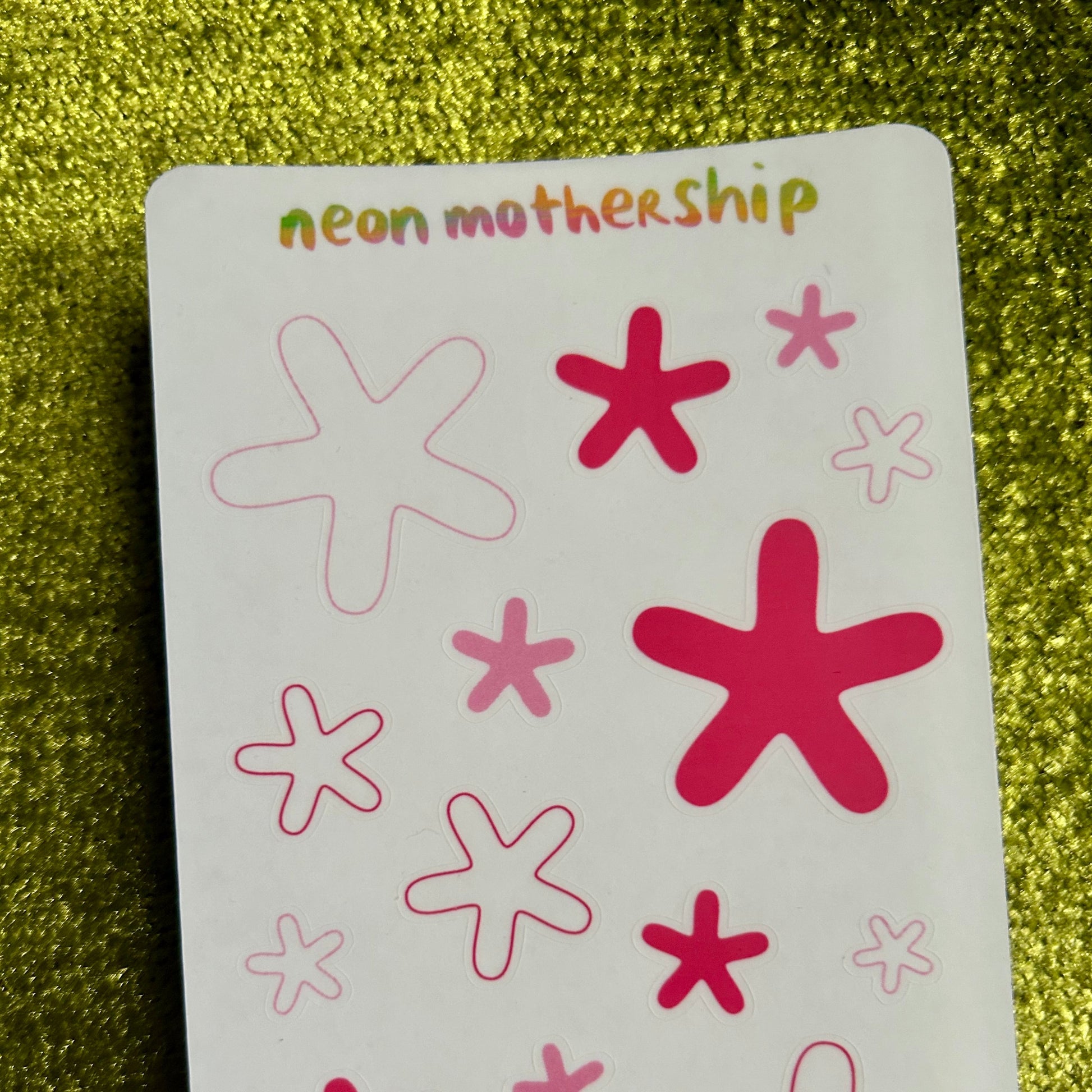 sticker sheet with red and pink star-shaped stickers on a green glittery background
