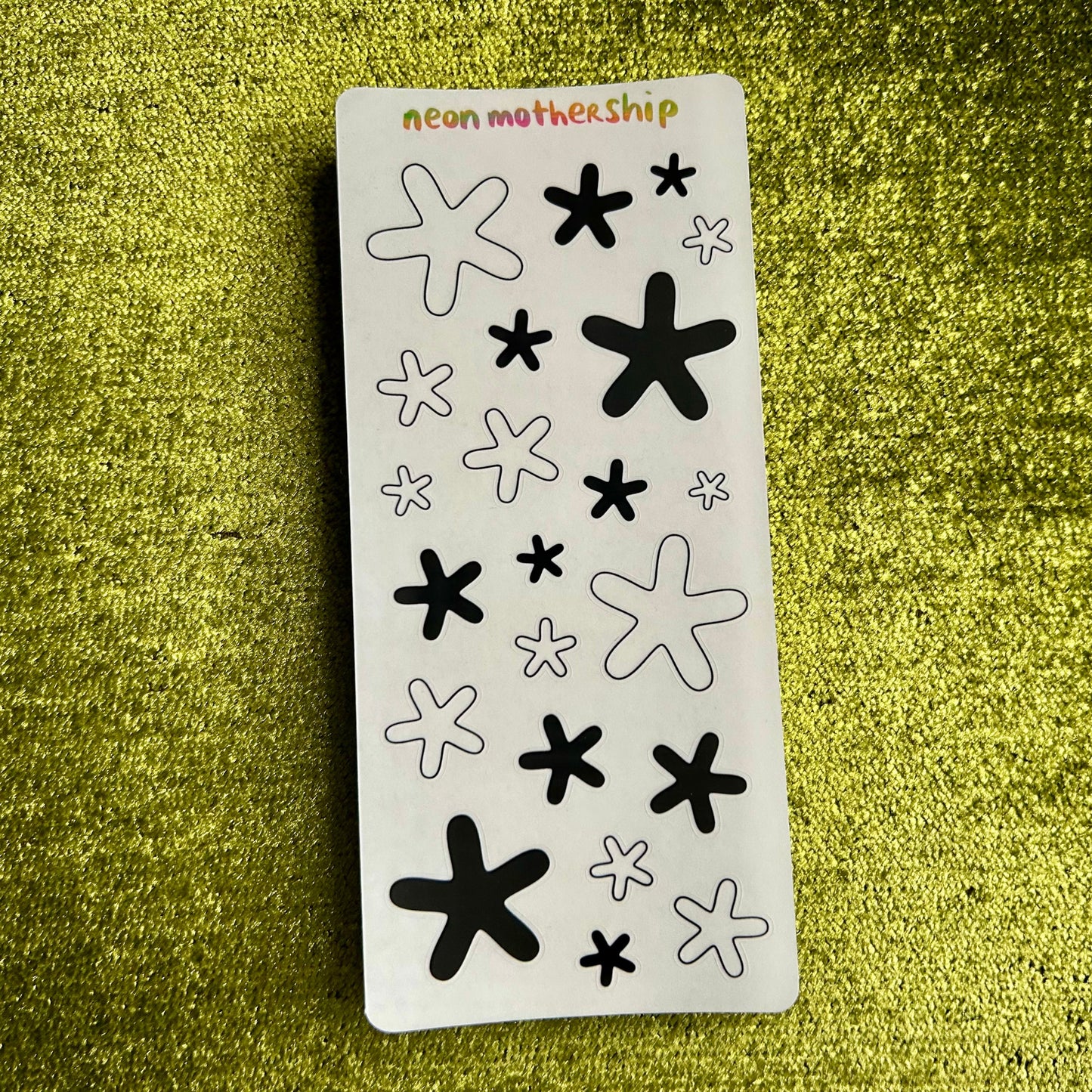 Sheet of black and white star-shaped stickers on a green textured background