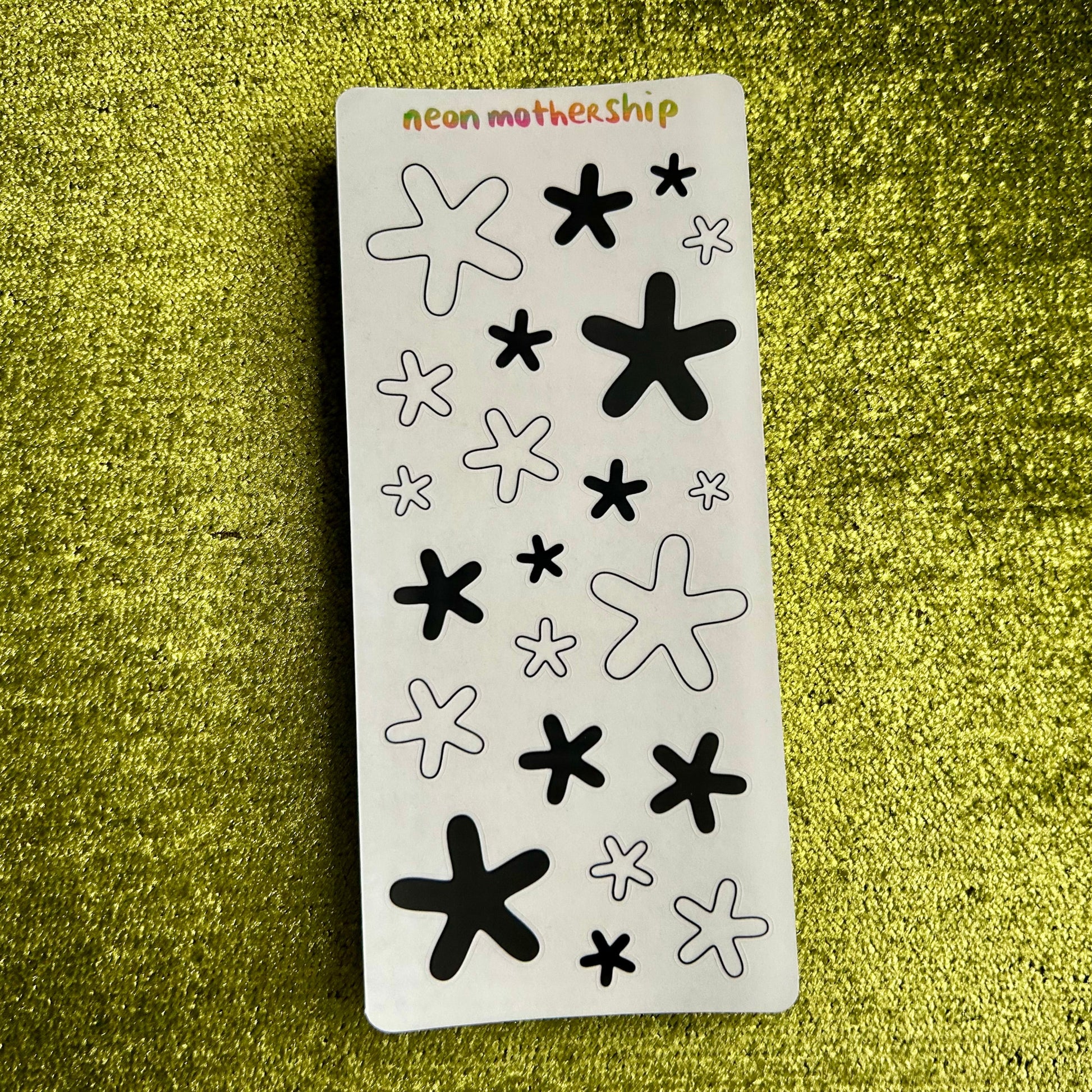 Sheet of black and white star-shaped stickers on a green textured background