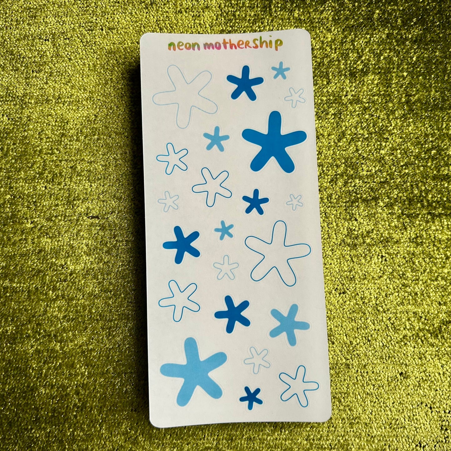 sticker sheet with blue and white starfish designs on a green textured surface