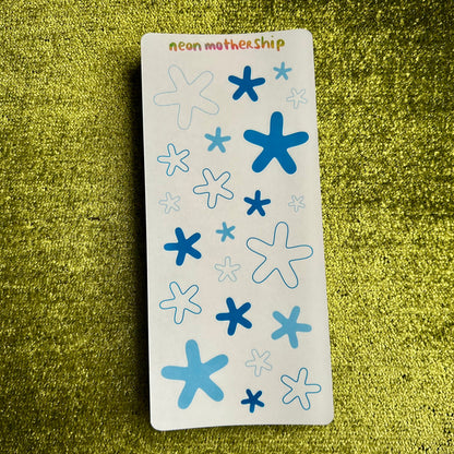 sticker sheet with blue and white starfish designs on a green textured surface