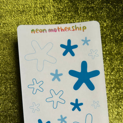 Sheet of blue star-shaped stickers on a green textured surface