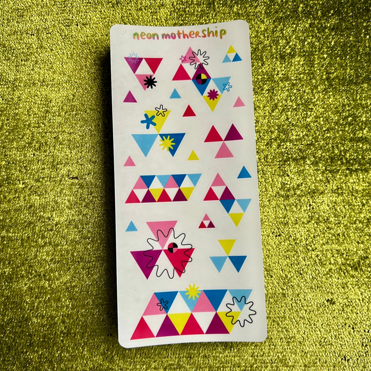 Sticker sheet with geometric triangle patterns on a green textured surface