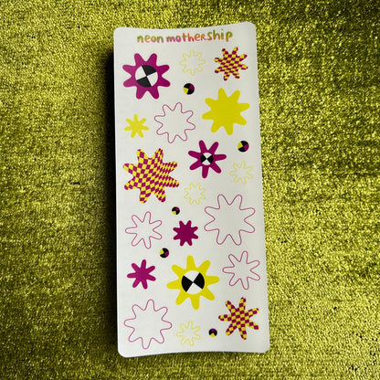 Sheet of colorful flower-shaped stickers on a green textured background