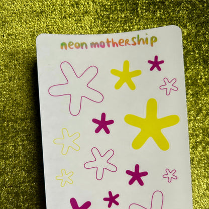 Sticker sheet with colorful star and asterisk patterns on a green glittery background