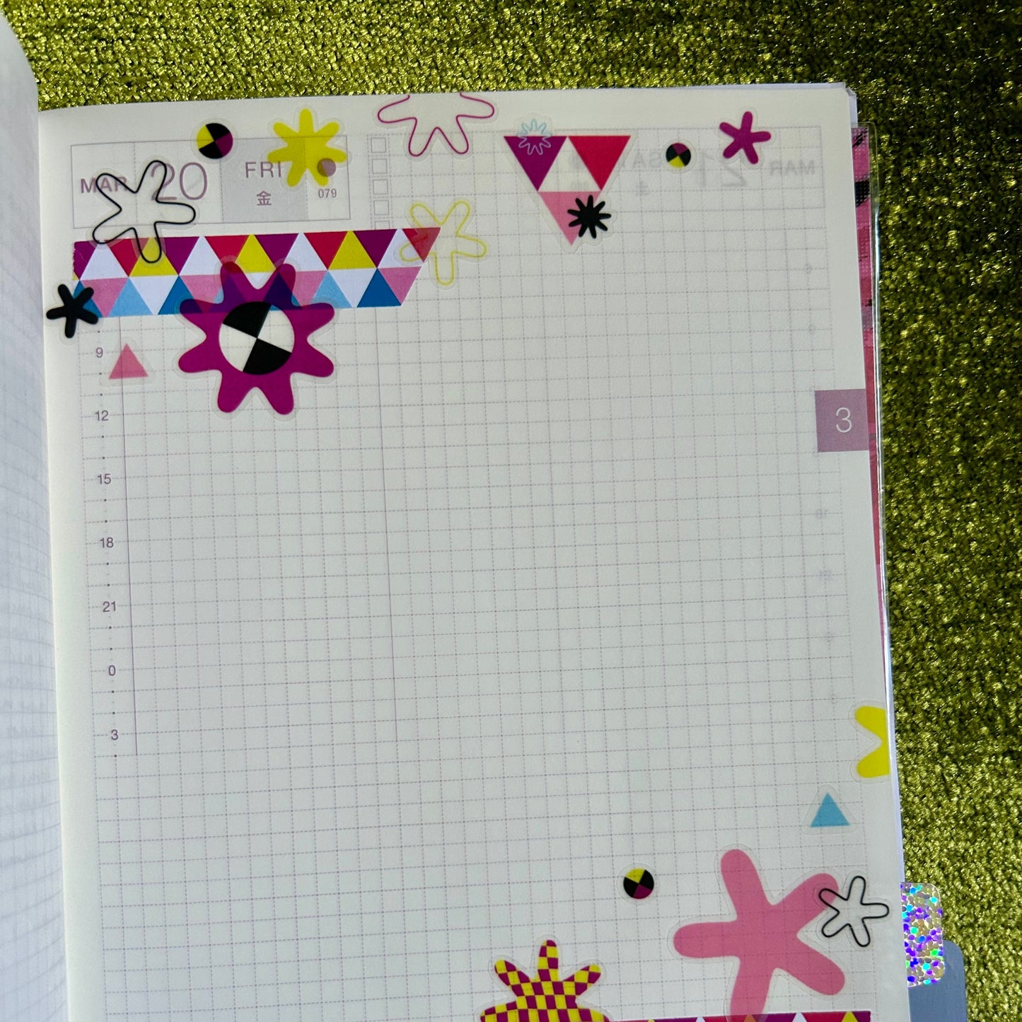 Notebook with colorful geometric stickers on a green textured surface