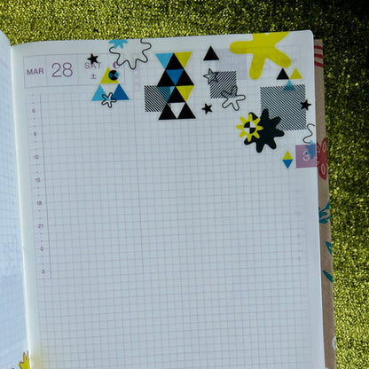 Notebook with geometric stickers on a green textured surface