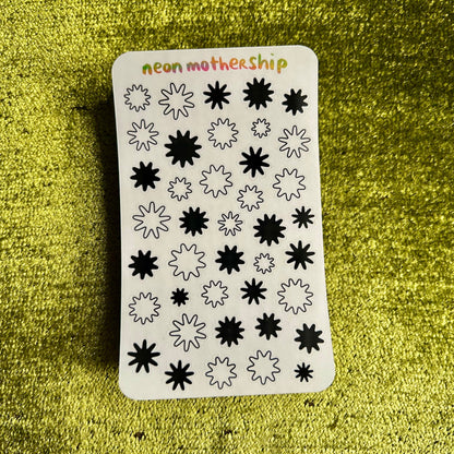 Sheet of black star-shaped stickers on a green textured background
