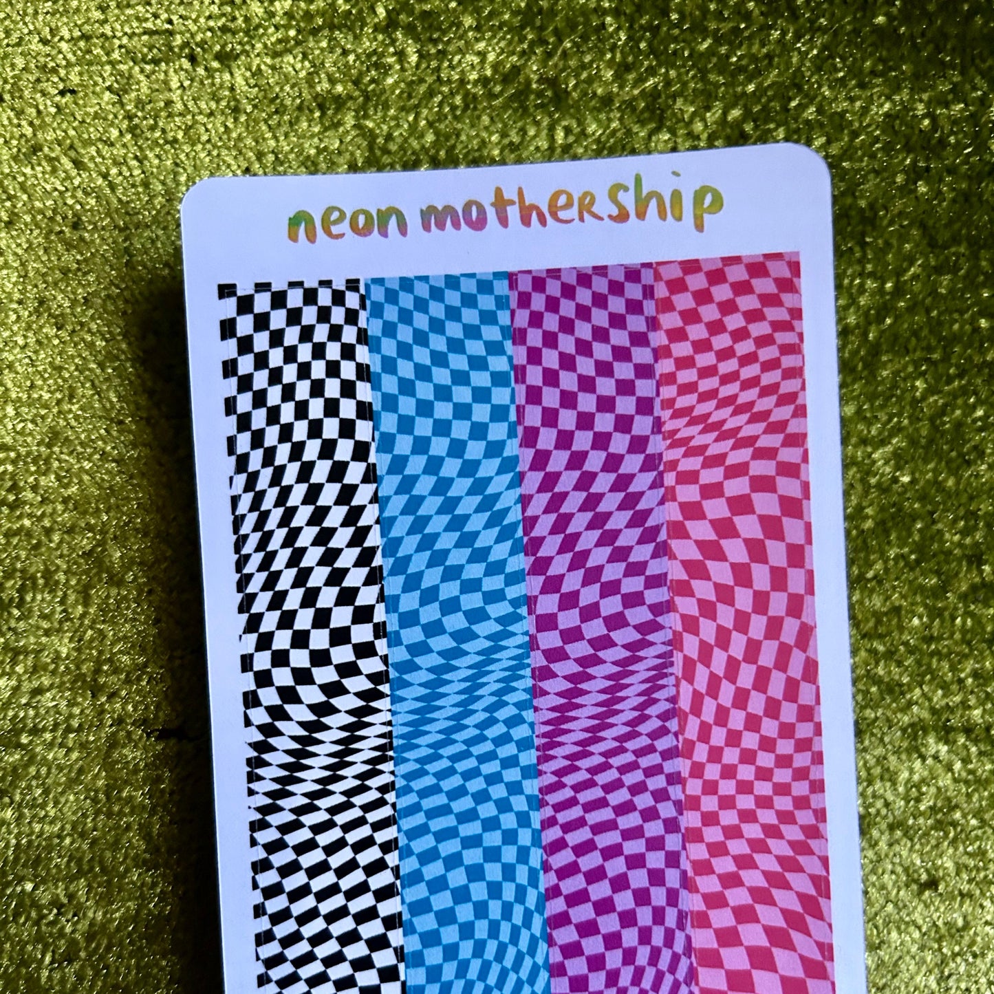 sticker sheet with 'neon mothership' text and colorful pattern on a green textured background