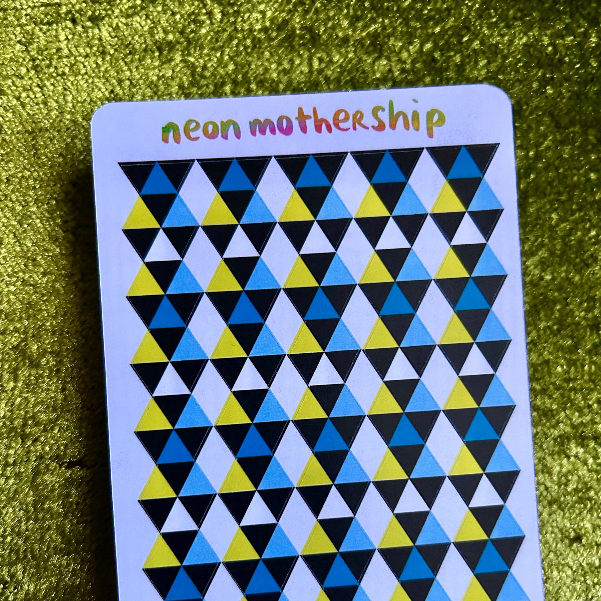 sticker sheet with geometric triangle pattern and 'neon mothership' text on a green textured background