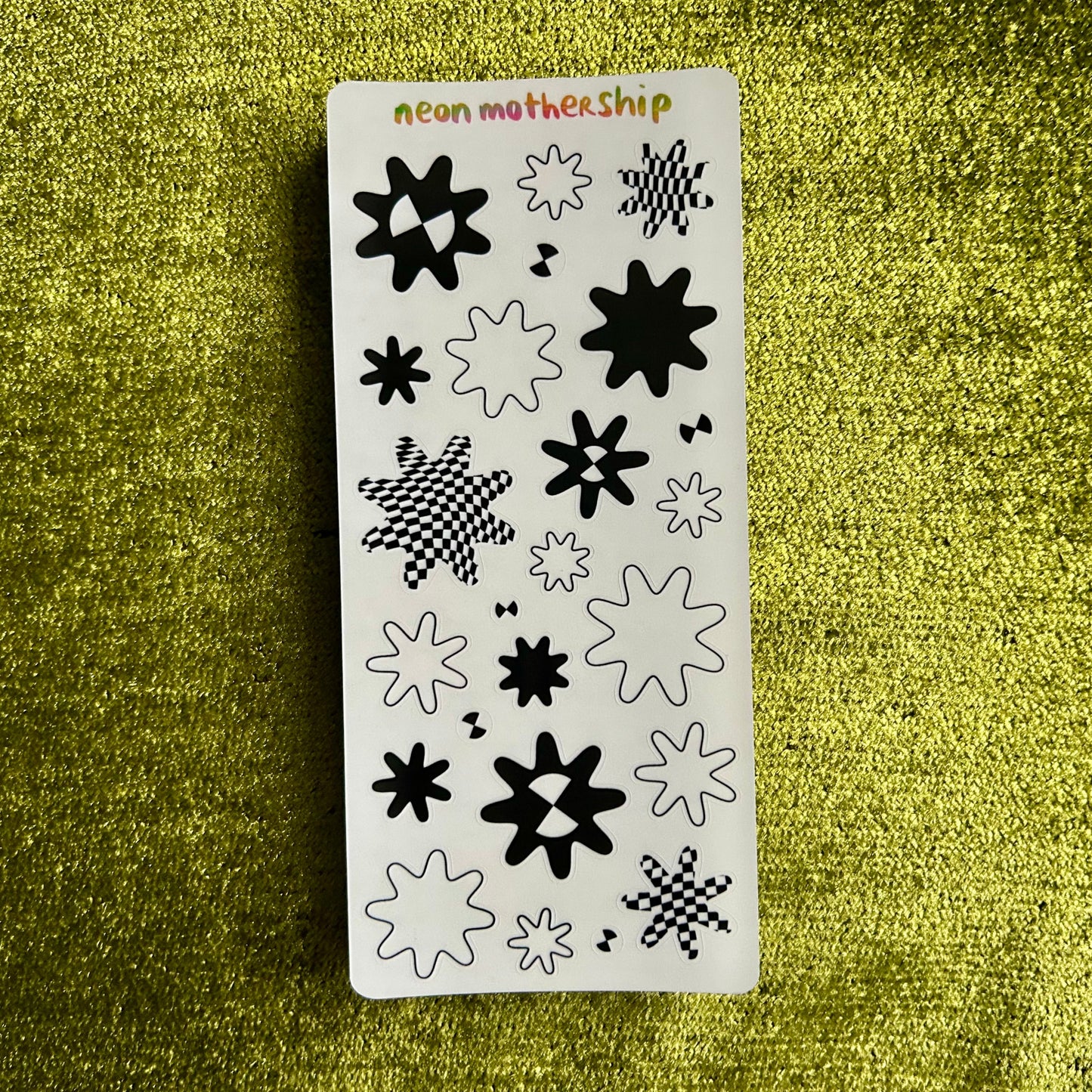 Sticker sheet with black star patterns on a green textured background