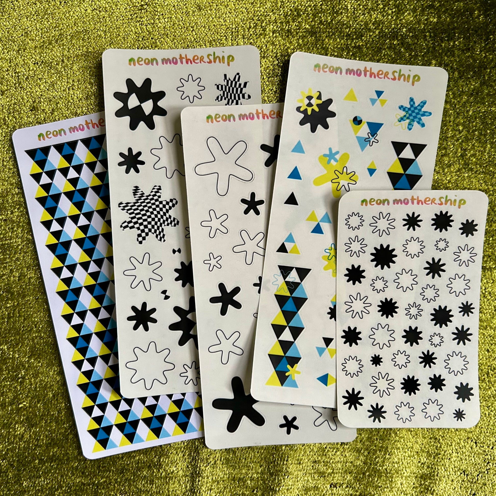 Set of five patterned sticker sheets on a green textured surface