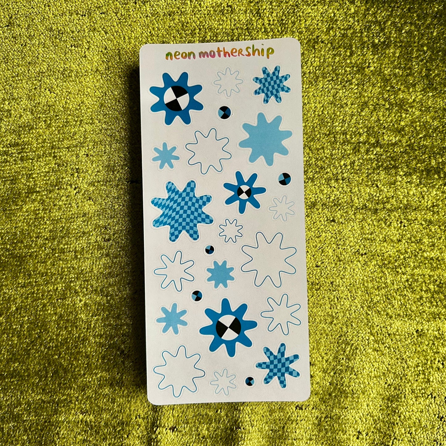Sticker sheet with blue and white floral designs on a green textured surface