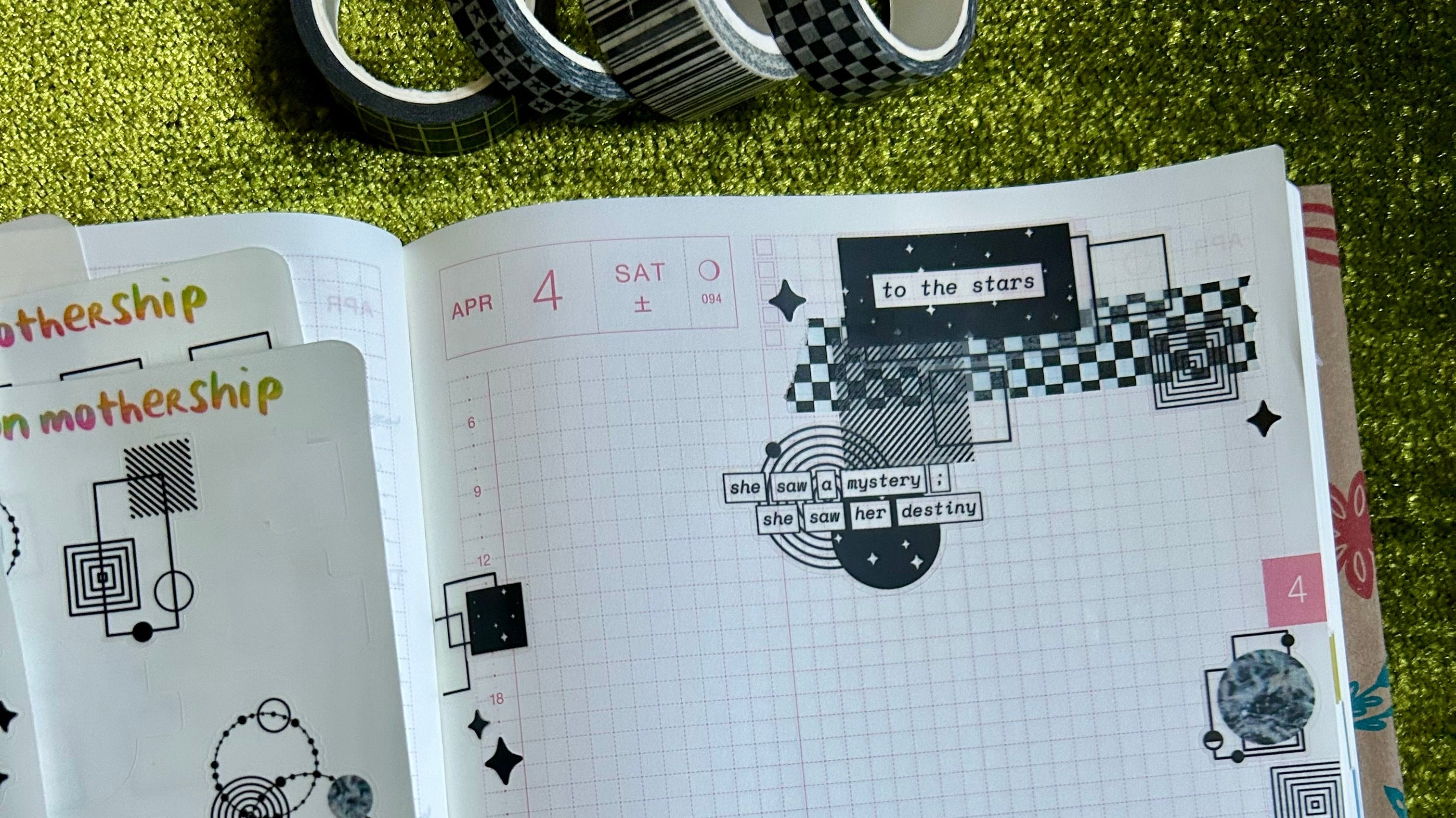 Open notebook with black and white designs on a green surface with tape and scissors.