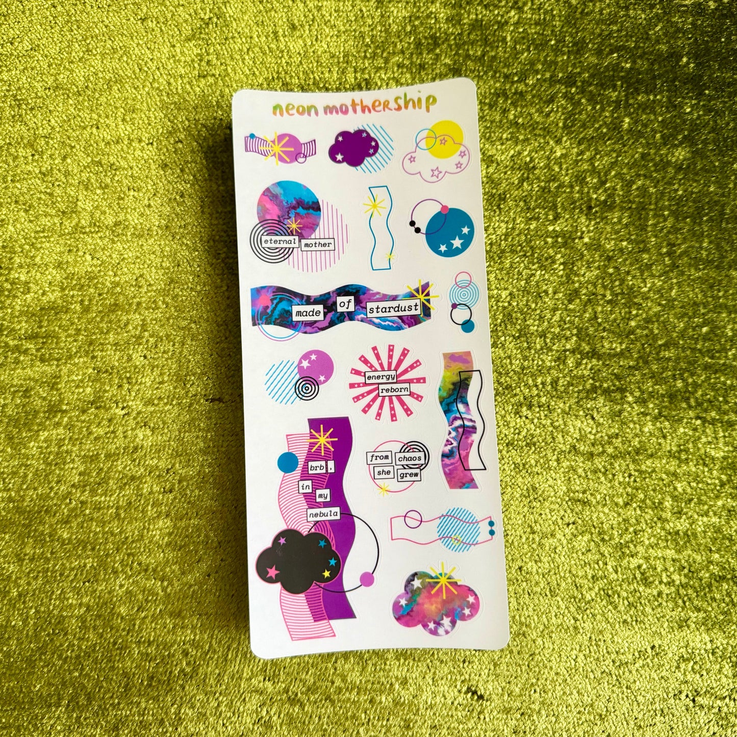Sticker sheet with colorful designs on a green textured surface