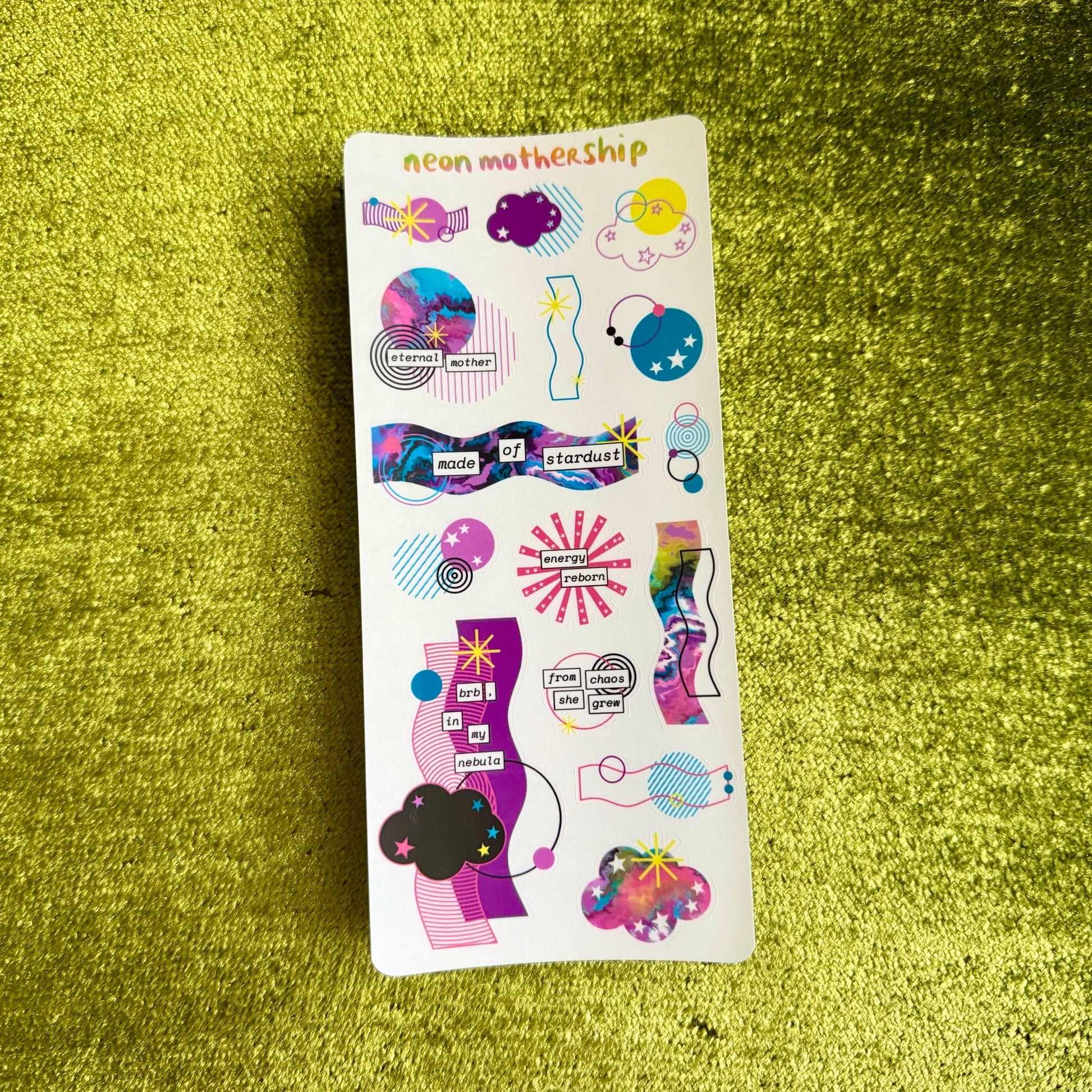 Sticker sheet with colorful designs on a green textured surface