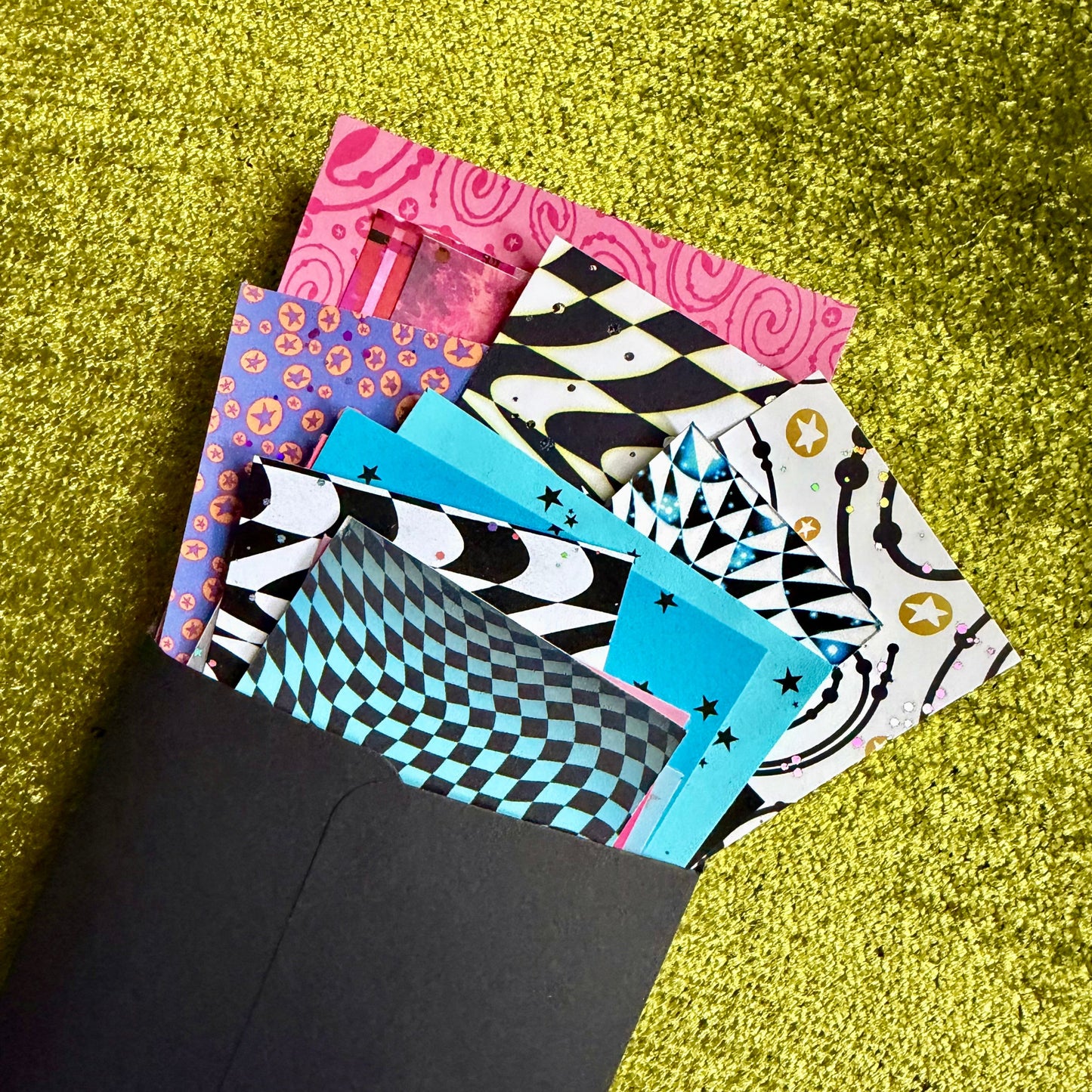 Colorful patterned papers on a green textured surface