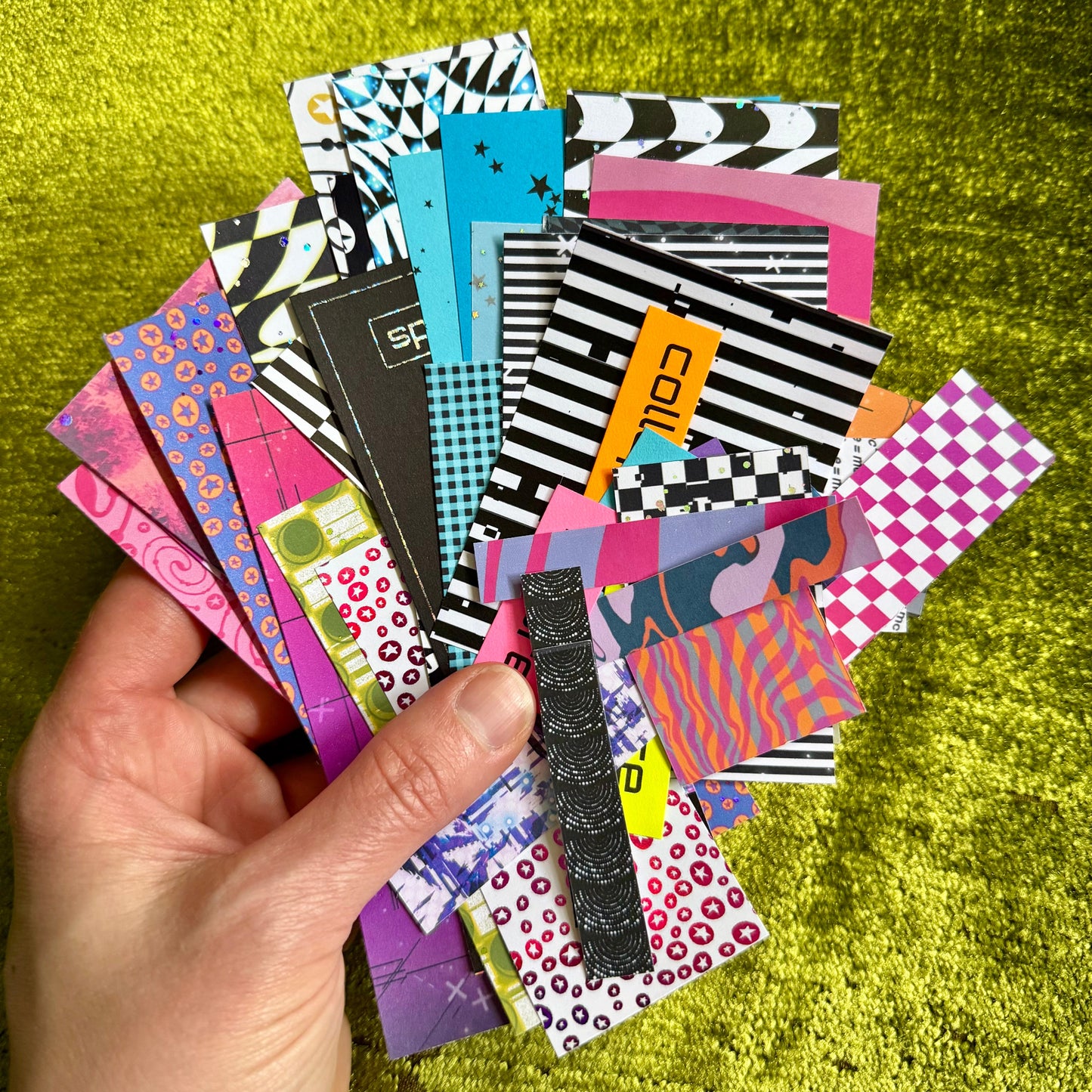 Hand holding a collection of colorful stationery items against a green textured background