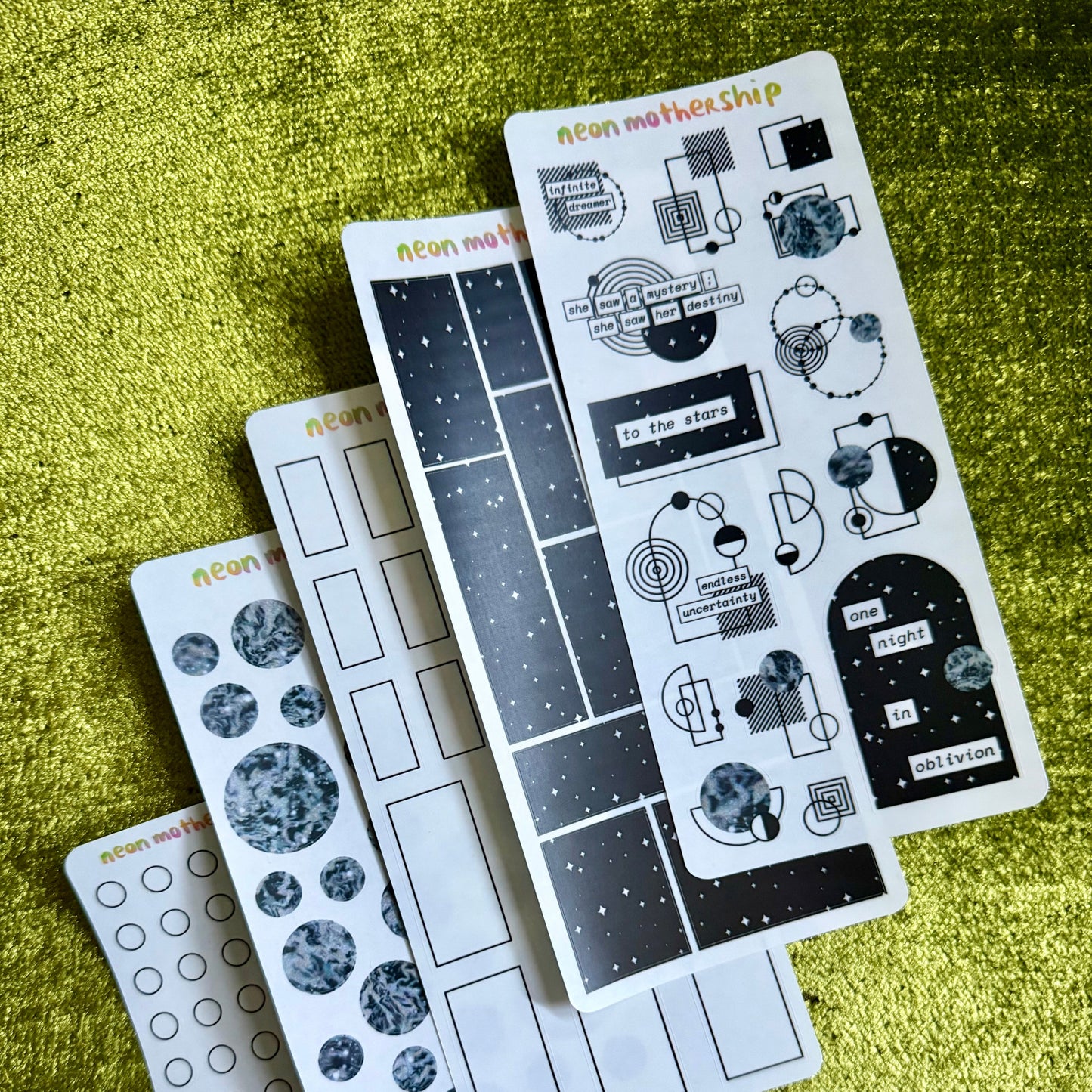 Set of sticker sheets with various designs on a green textured surface