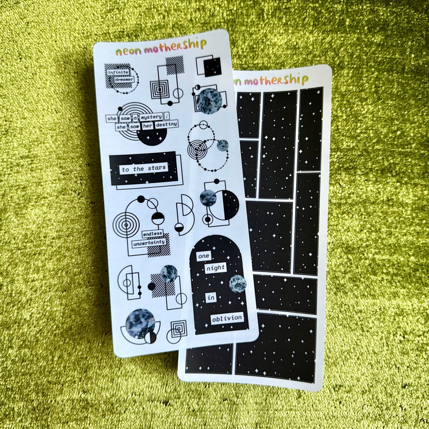 Two sheets of stickers with geometric designs on a green textured surface