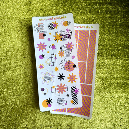 Two sheets of decorative stickers with colorful designs on a green textured surface.