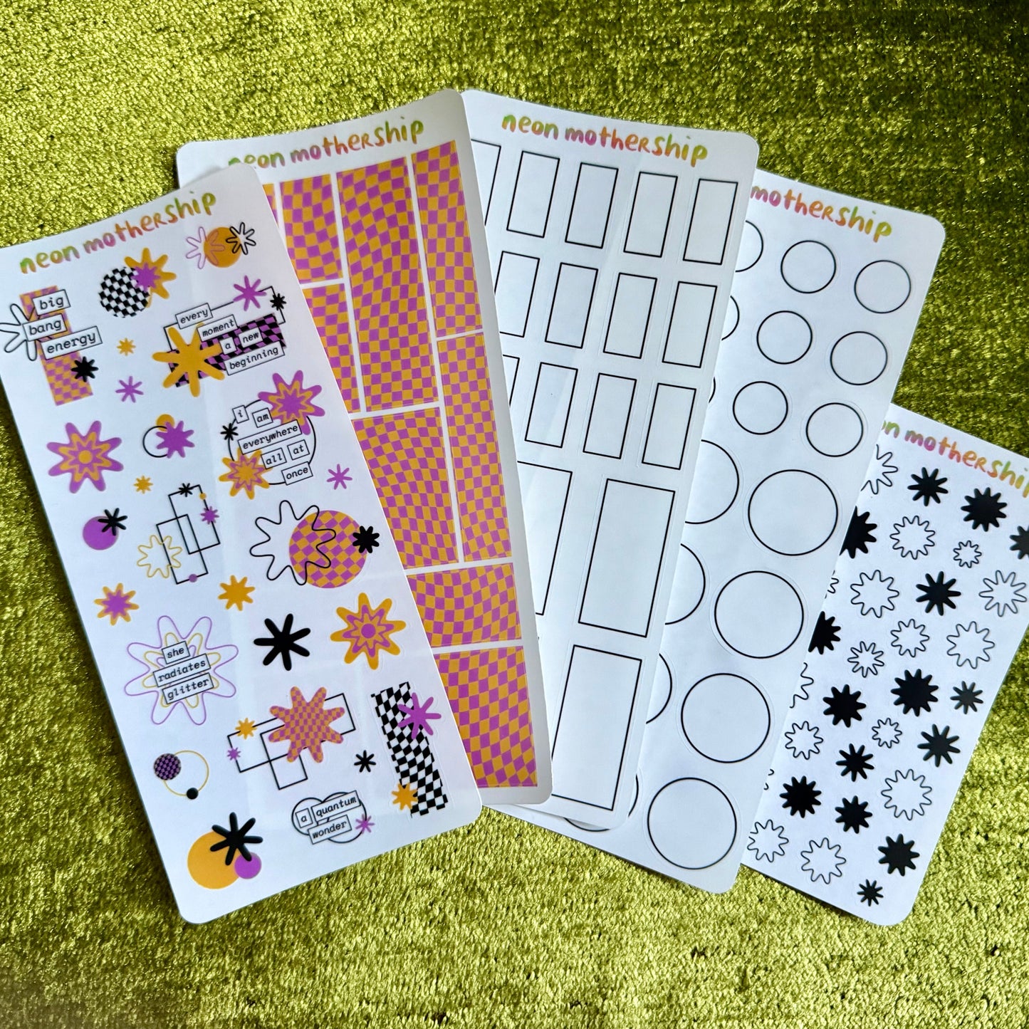 five sheets of colorful stickers on a green textured surface