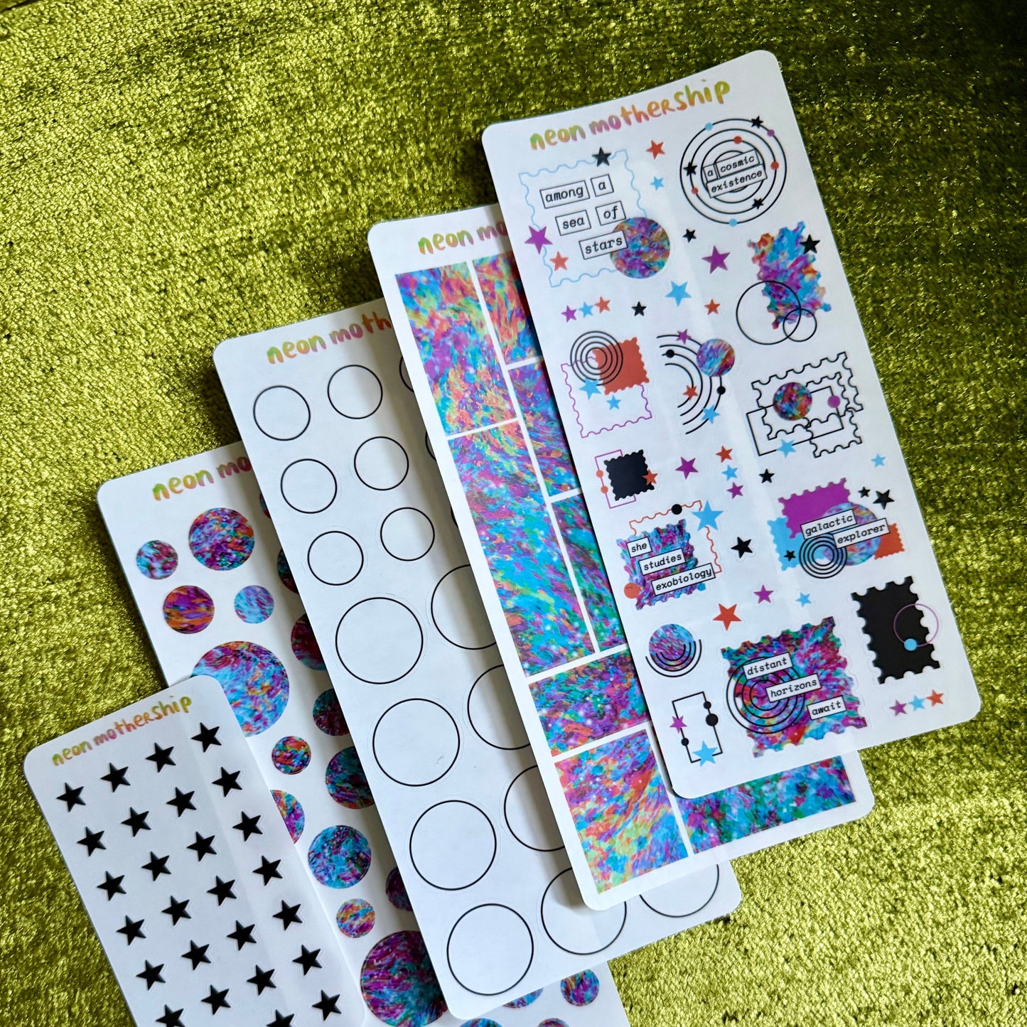 Set of colorful sticker sheets on a green textured surface