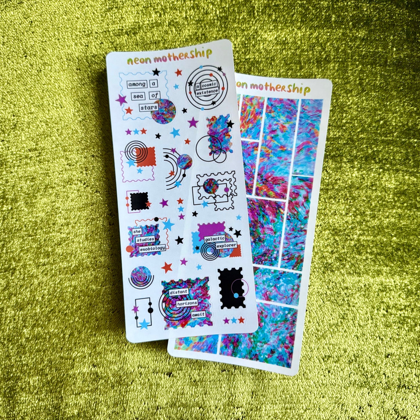 Two sheets of colorful stickers on a green textured surface