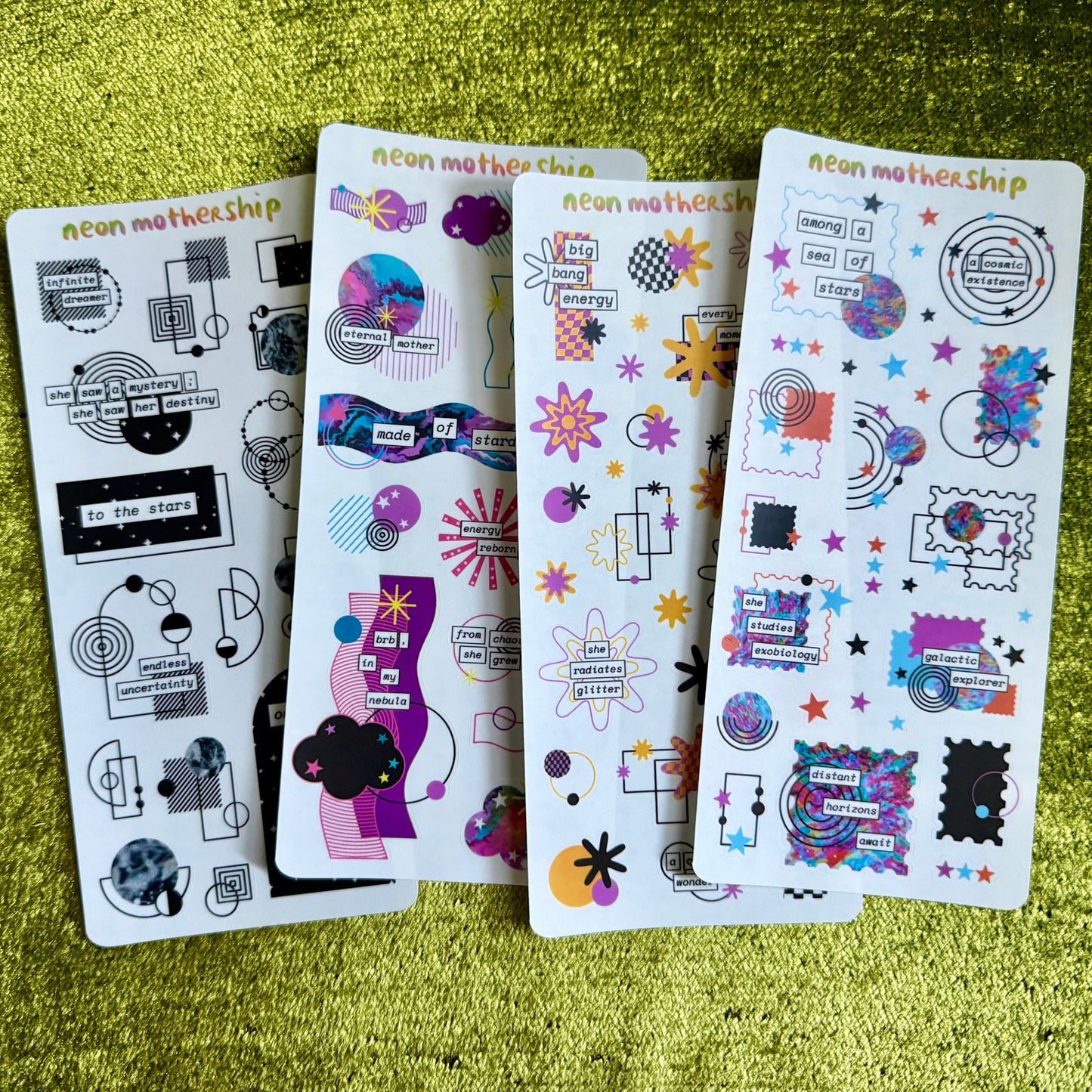 Four sheets of colorful stickers on a green textured surface