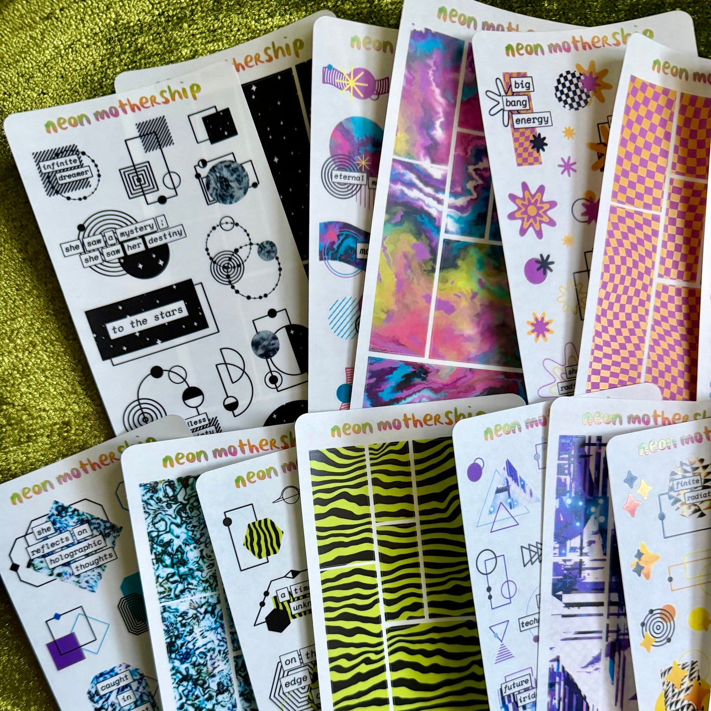 Collection of colorful sticker sheets on a green textured surface