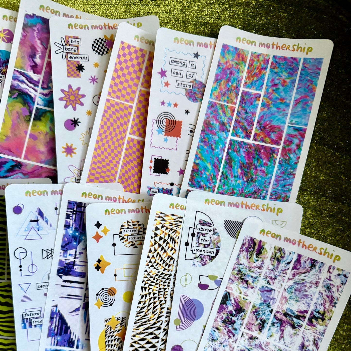 Collection of colorful sticker sheets with various designs on a green surface.